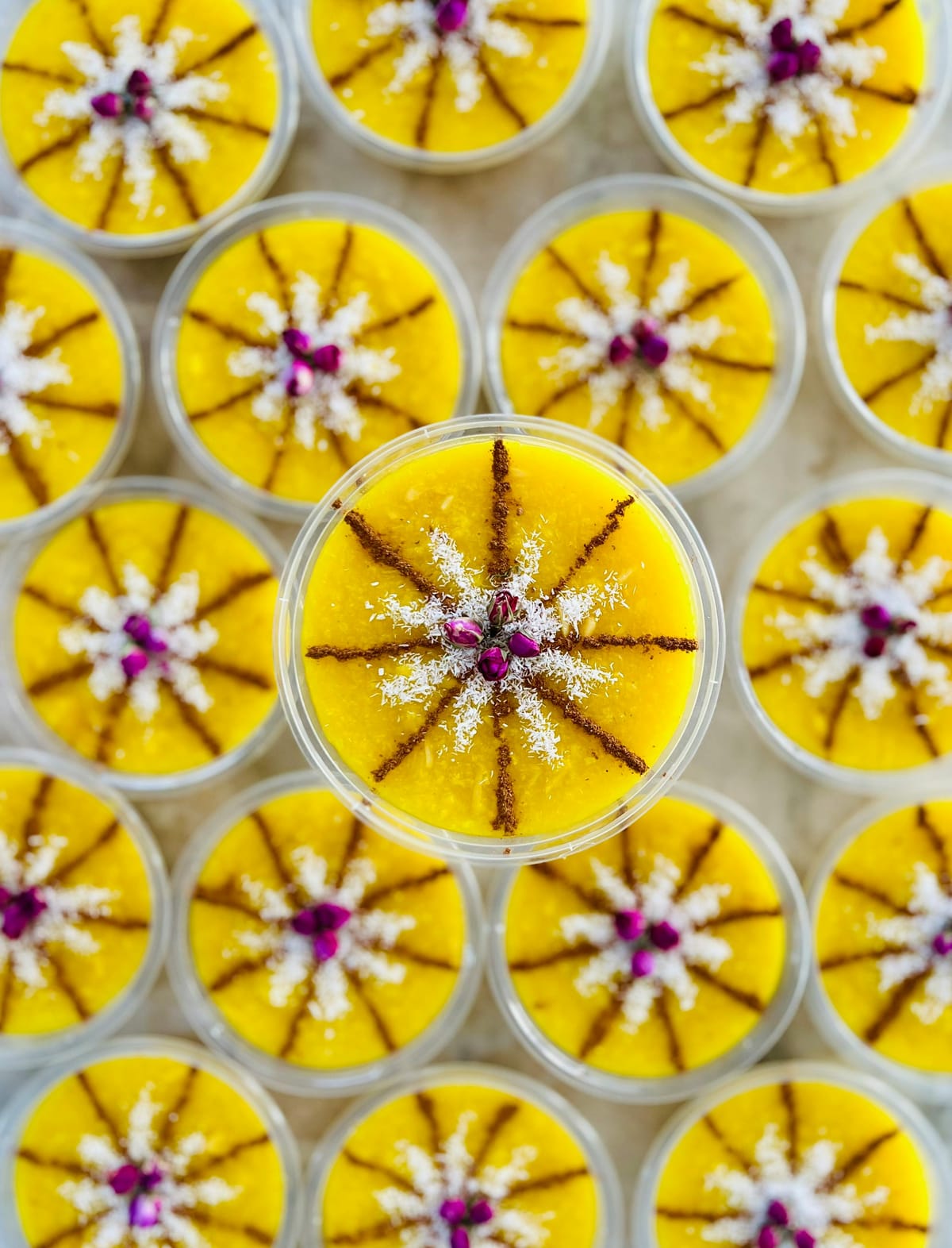 Cups of Persian sholeh zard saffron rice pudding garnished with cinnamon, coconut and dried rose petals