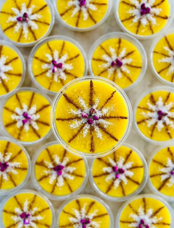 Cups of Persian sholeh zard saffron rice pudding garnished with cinnamon, coconut and dried rose petals