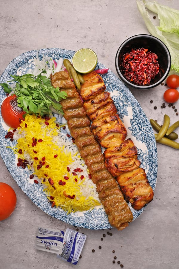 Persian Zereshk Polo barberry saffron rice with Koobideh and Joojeh chicken kabab on a blue patterned plate