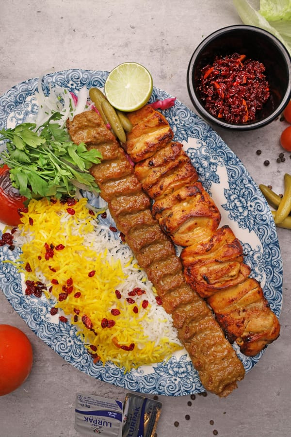 Persian Chelo saffron steamed rice with Koobideh and Joojeh kabab on a blue patterned platter